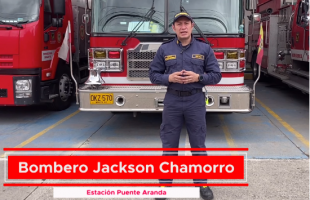 Bombero de pie con un camión de bomberos atrás