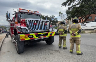 Bomberos parados al frente del camión de bomberos