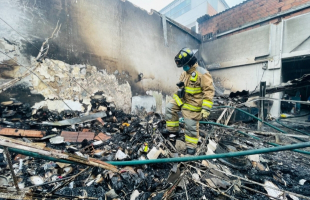 Bombero sobre las cenizas de una empresa