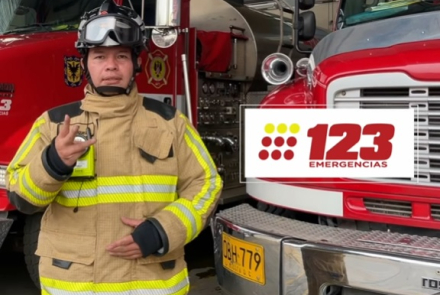 Bombero frente a la cámara con un aviso del teléfono de emergencias 123