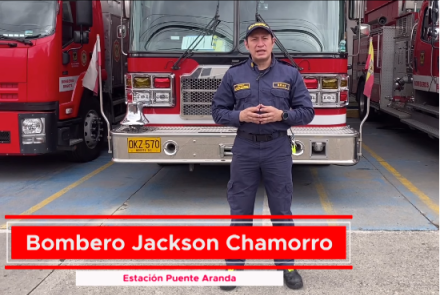 Bombero de pie con un camión de bomberos atrás