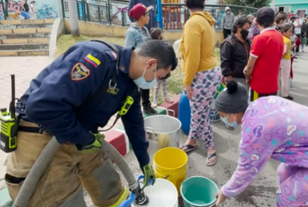 Bombero ayudando a la comunidad llenado baldes de agua
